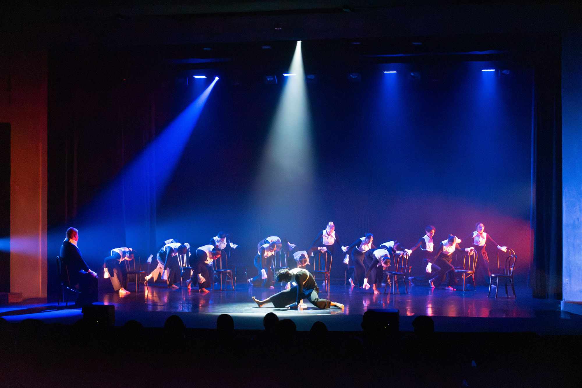 A line of students in black suits surrounding a girl doing the splits