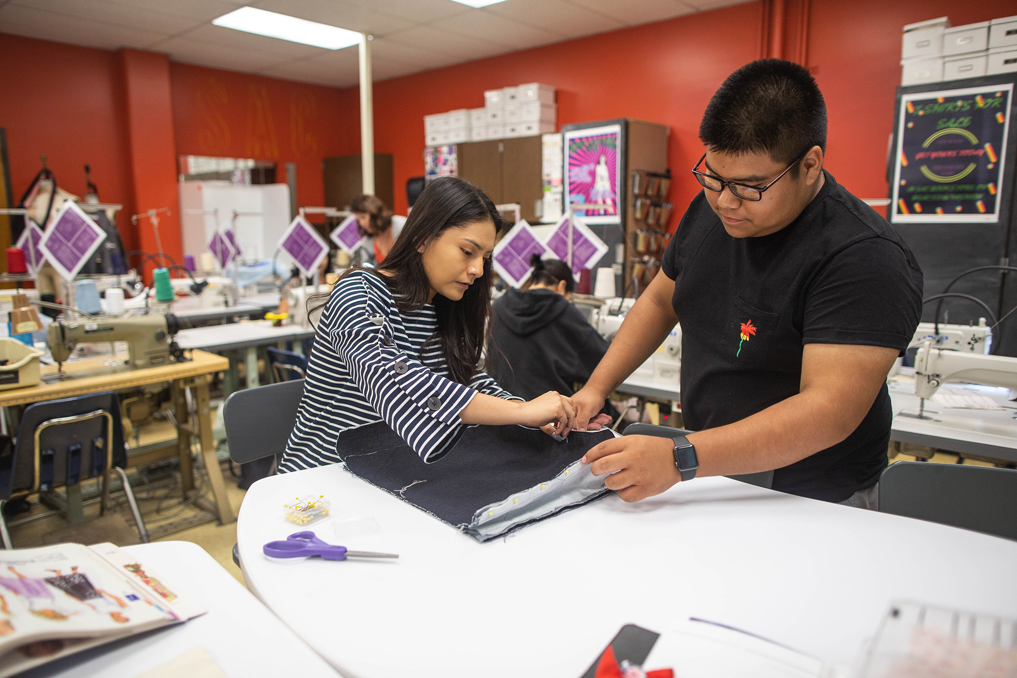 female and male student measuring fabric