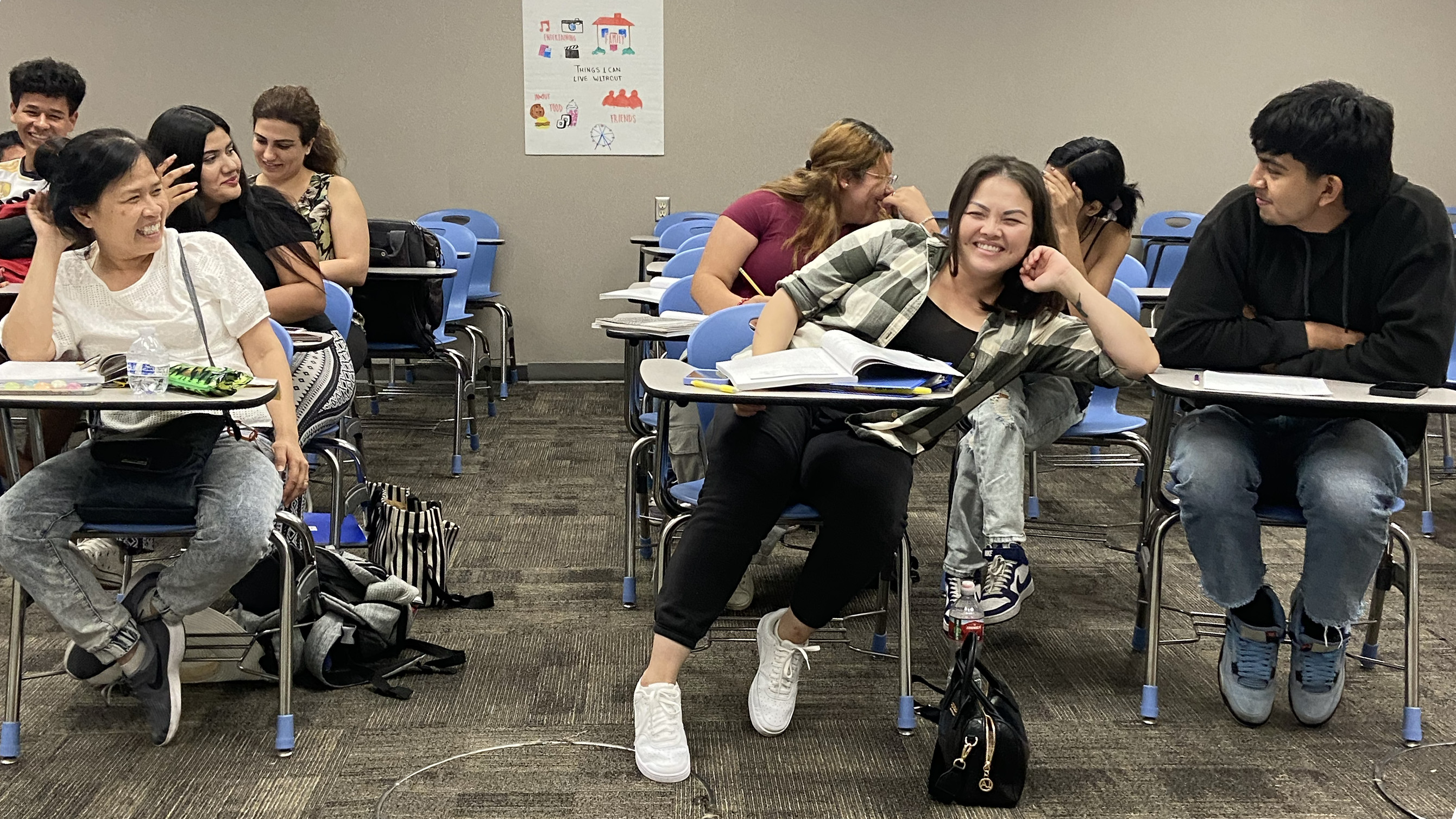 smiling asian female student leaning on another student's desk 