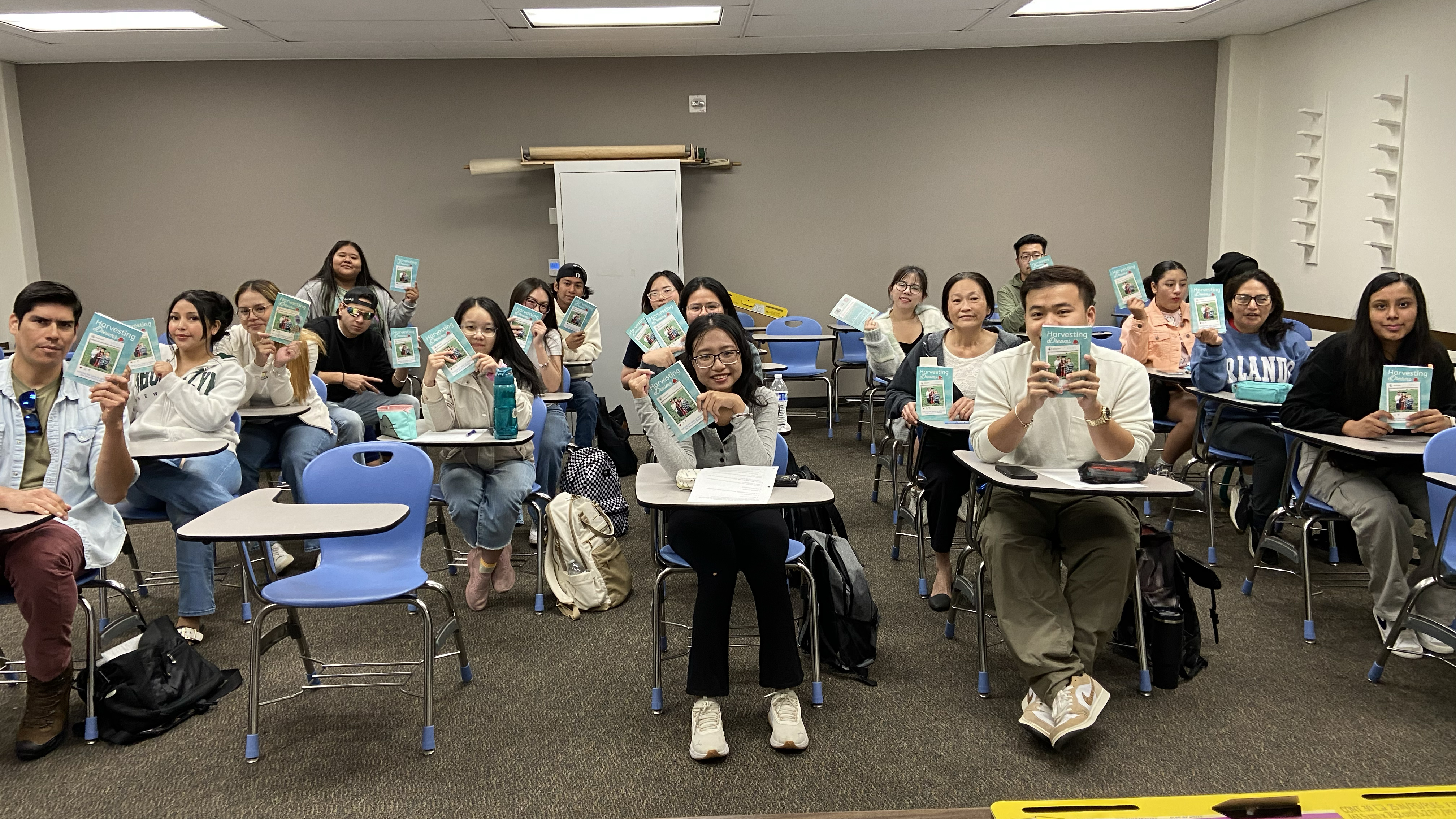 students seated in classroom holding up a book