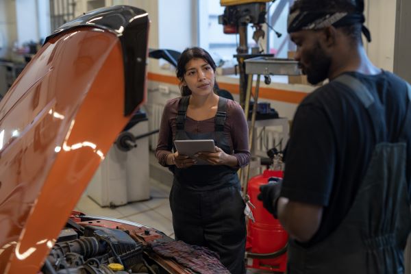 Hispanic female and black male student working on a car