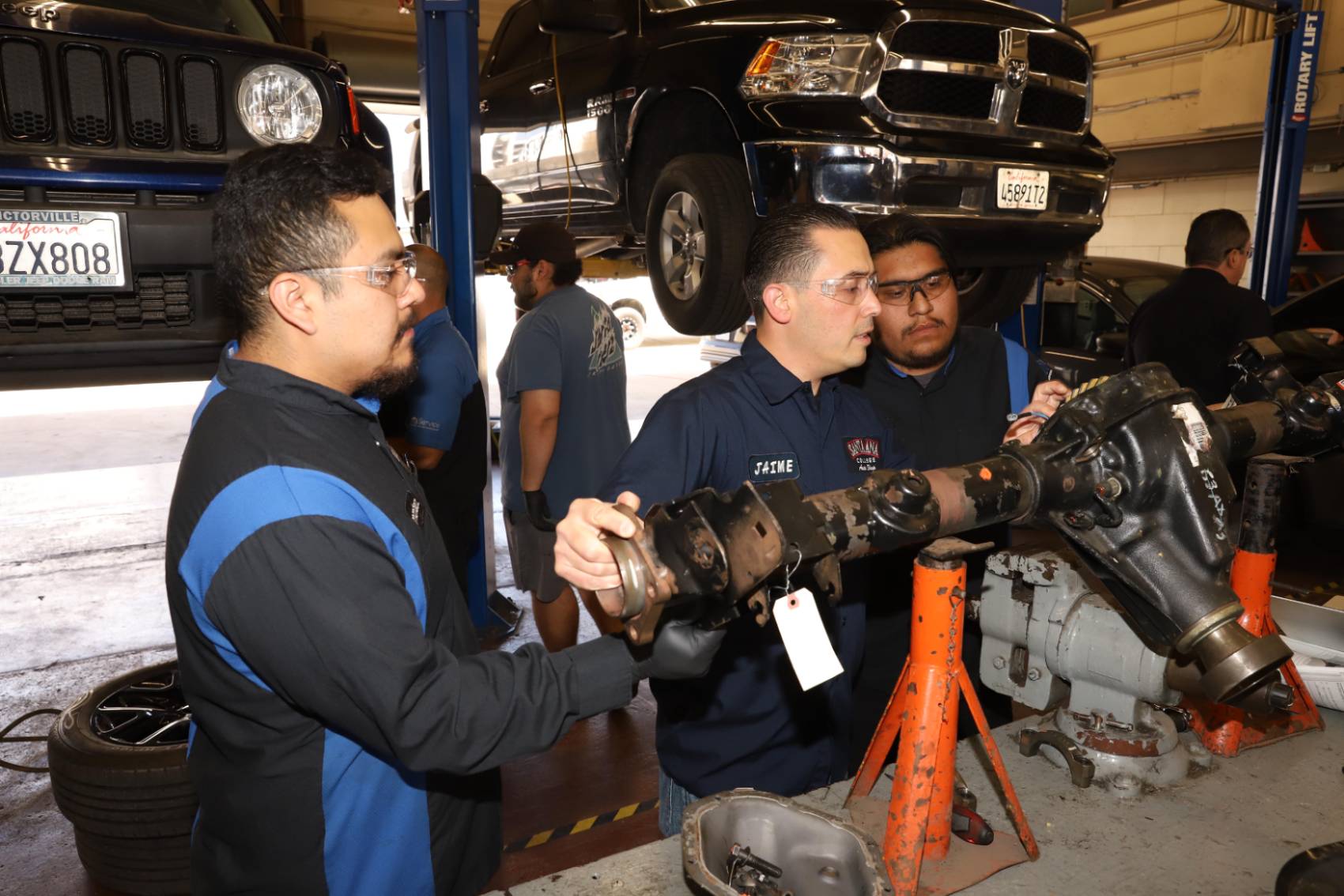 two autotech students learning about a chassis from an instructor