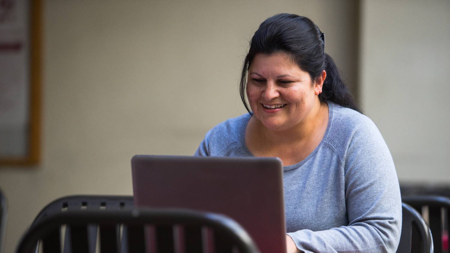 WHite female student taking classes outside on a laptop