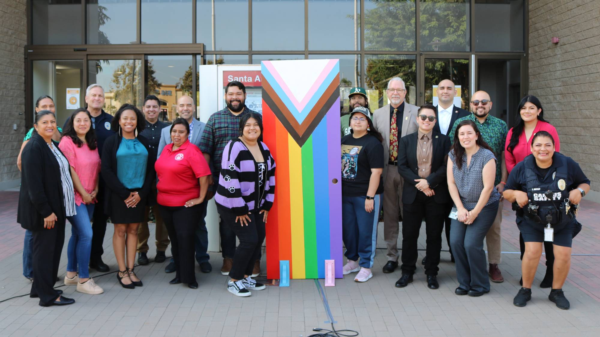 Staff, faculty, and students standing around the Pride flag