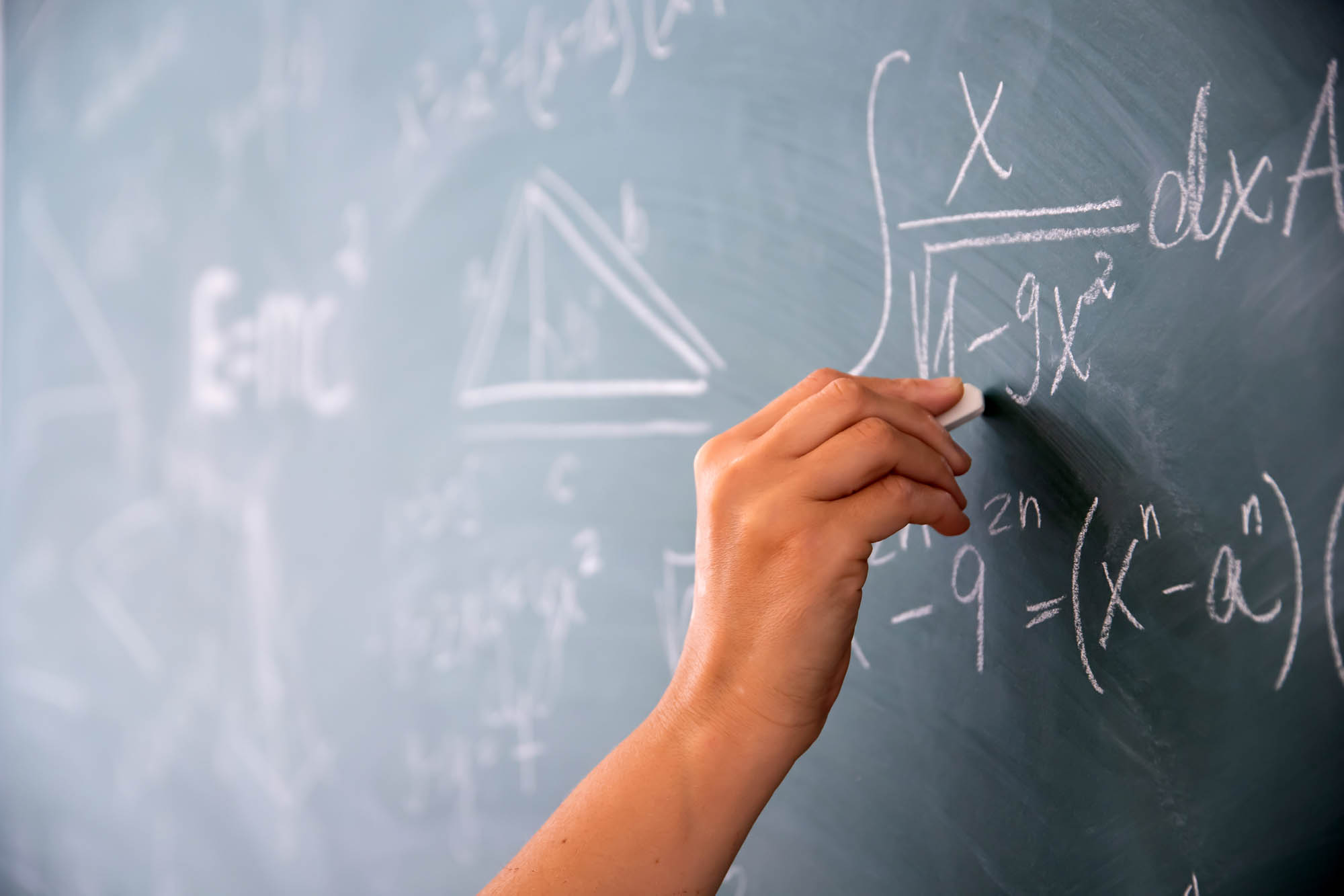 hand solving math problems on chalkboard