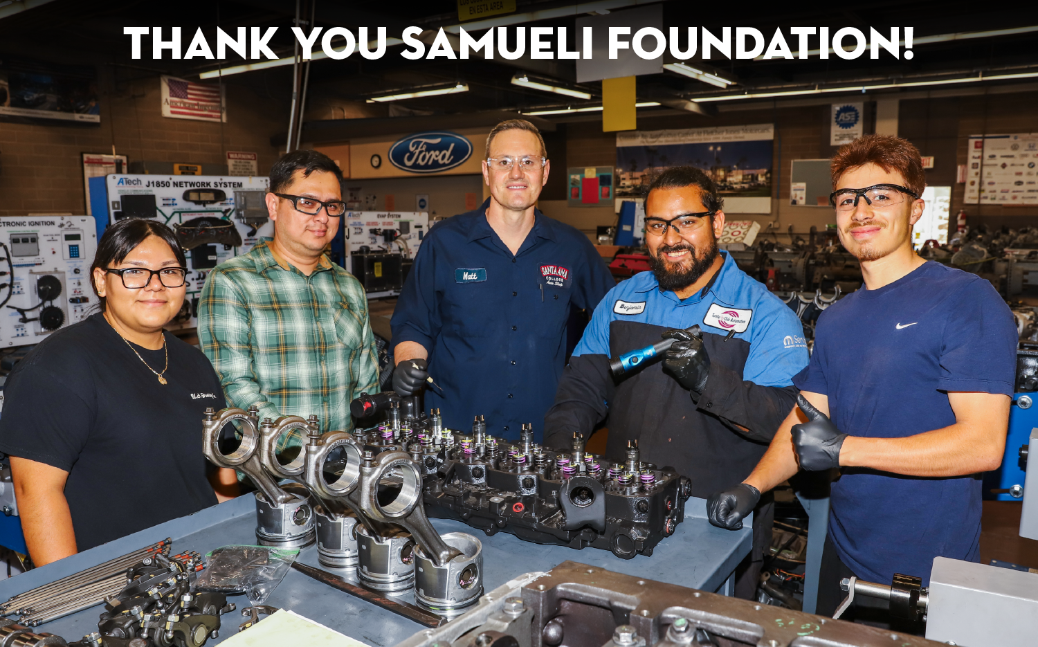 Auto Tech students smiling in front of engine model with a "Thank you Samueli Foundation" message above them